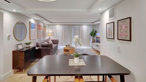 A modern living room with a dining table, sofa, and a TV. - Modern 2-Bedroom in Central South Beach Location (Miami Beach)