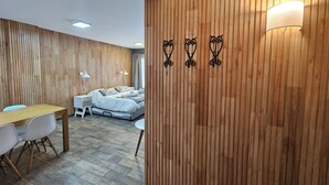 Une chambre moderne avec un mur recouvert de panneaux en bois, un lit avec une literie blanche, un bureau avec une chaise et deux lampes fixées au mur.
