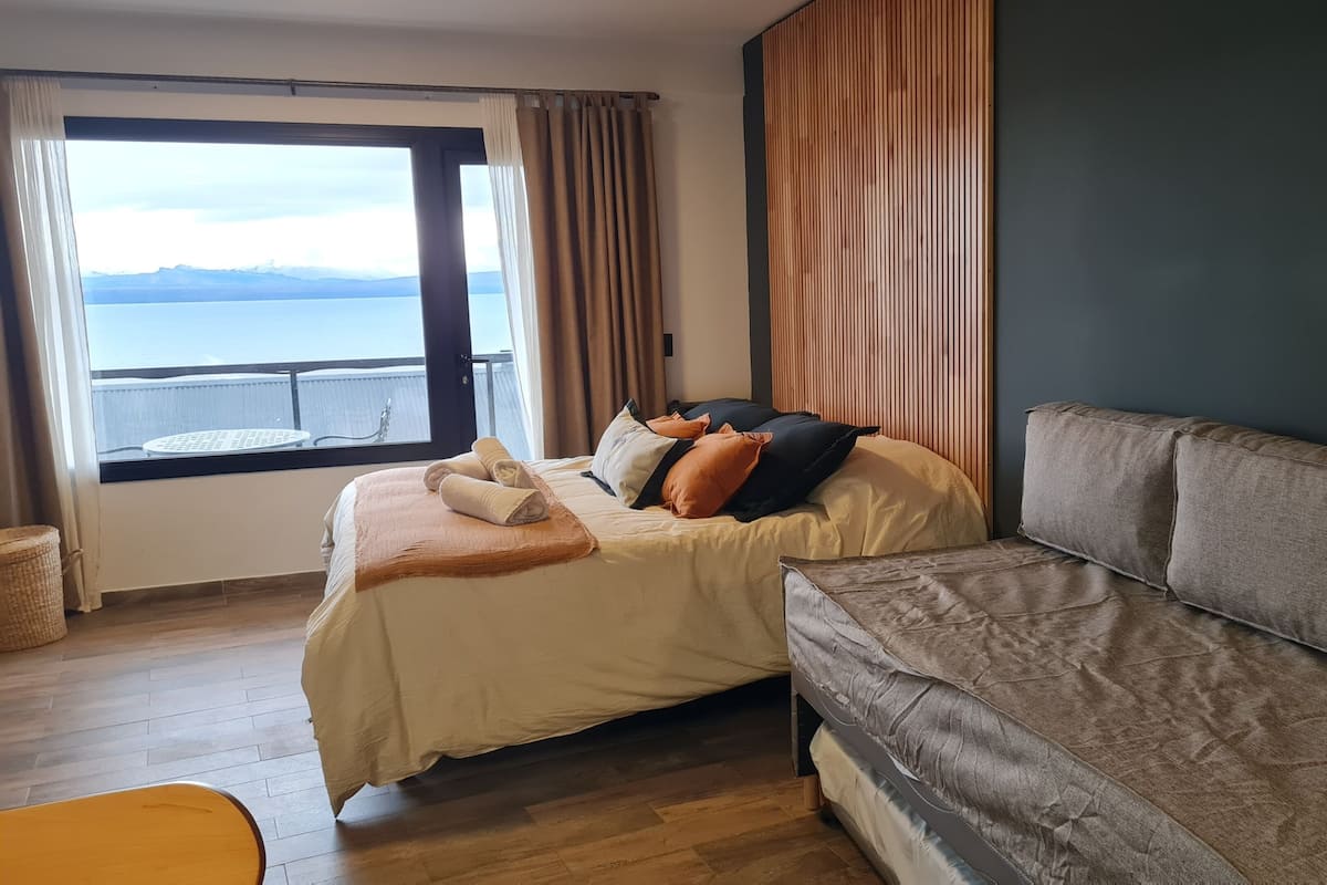 Habitación de hotel con cama, sofá, vista al mar y balcón.