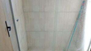A small bathroom with a shower, toilet, and a mat on the floor. - Nice house, one block from the sea.  (Arroio do Sal)