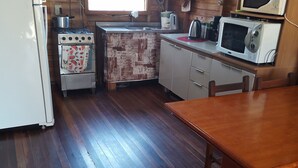 A wooden cabin-style kitchen with a refrigerator, stove, microwave, and wooden dining table. - Nice house, one block from the sea.  (Arroio do Sal)