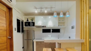Une cuisine moderne dotée d’appareils électroménagers en acier inoxydable, de meubles blancs et de tabourets en bois.