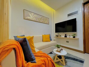 Un salon moderne avec un canapé, un téléviseur et une petite table agrémentée de plantes.