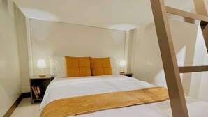 Un lit superposé avec une échelle, une literie blanche et deux tables de chevet avec des lampes.