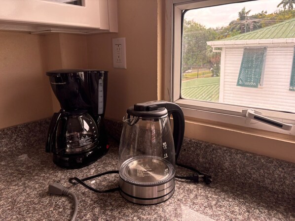 A kitchen counter with a coffee maker, a kettle, and a blender. - Carmichael Suites (Georgetown)