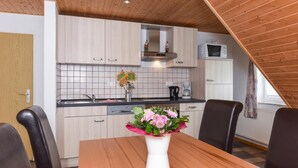 A modern kitchen with light wood cabinets, a tiled backsplash, and a wooden ceiling. - House Hafeneck FeWo Deichblick (Bensersiel)