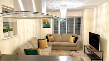 A modern living room with a sofa set, a flat-screen TV, and a gas stove.