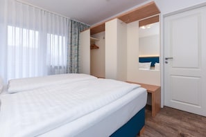 Une chambre à coucher avec un lit, un banc en bois, une armoire et une porte.