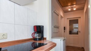 A kitchen with a black coffee maker, a white refrigerator, and a wooden ceiling.