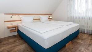 Ein Doppelbett mit Holz-Kopfteil und Nachttischen, ein blauer Akzent am Bettgestell und ein Holzboden.