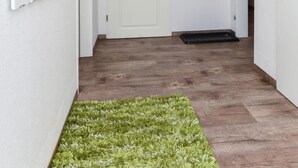 Ein Korridor mit Holzboden, weißen Wänden und einem grünen Teppich.