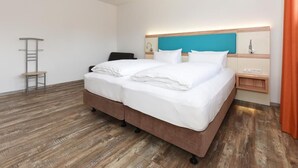 A hotel room with a large bed, a nightstand, a lamp, and a wooden floor. - Haus zur Möwe apartment Möwe 1 (Bensersiel)