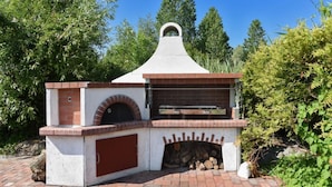 An outdoor brick oven with a chimney, a fire pit, and a picnic table. - Haus zur Möwe apartment Möwe 1 (Bensersiel)