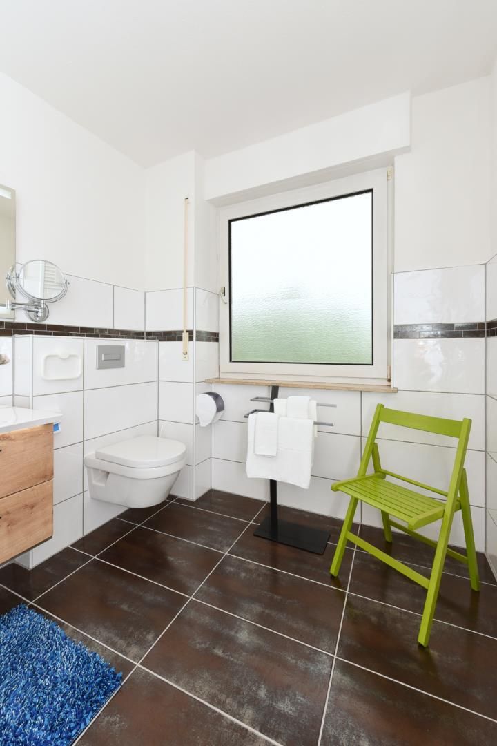 A bathroom with a toilet, sink, mirror, and a window.