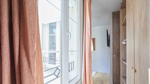 Quarto com uma janela grande, um guarda-roupa de madeira e uma porta com puxador.