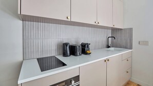 Uma cozinha moderna com bancada branca, eletrodomésticos de aço inoxidável e armários em tons claros.