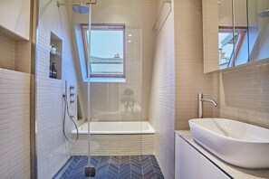 A modern bathroom with a glass-enclosed shower, a freestanding bathtub, and a large sink.