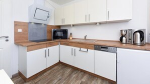 A modern kitchen with white cabinets, a microwave, a coffee maker, and a dishwasher. - Haus zur Möwe apartment Möwe 2 (Bensersiel)