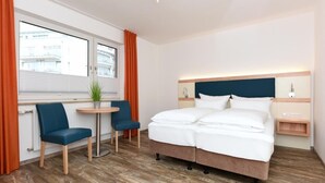 A hotel room with a bed, two chairs, a small table, and a window with curtains. - Haus zur Möwe apartment Möwe 2 (Bensersiel)