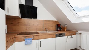 A kitchen with a wooden countertop, white cabinets, a black stove, and a skylight. - Haus zur Möwe apartment Möwe 4 (Bensersiel)