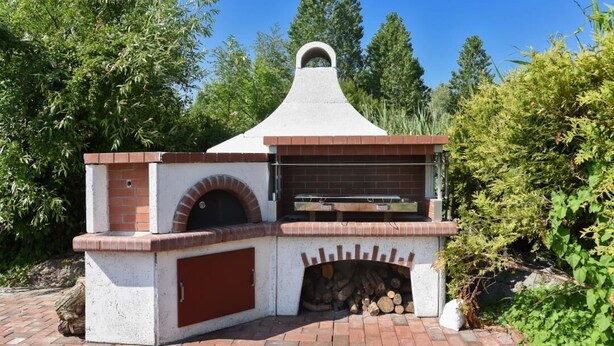 An outdoor brick oven with a chimney, a fire pit, and a picnic table. - Haus zur Möwe apartment Möwe 5 (Bensersiel)