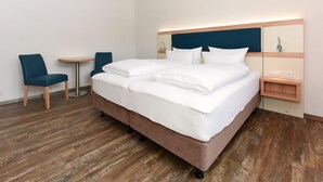 A hotel room with a large bed, two chairs, a small table, and a bedside table with a lamp. - Haus zur Möwe apartment Möwe 5 (Bensersiel)