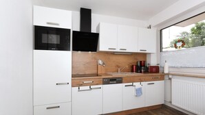 A modern kitchen with white cabinets, a black microwave, and a wooden countertop. - Haus zur Möwe apartment Möwe 5 (Bensersiel)