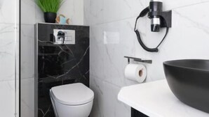 A modern bathroom with a toilet, sink, and a black marble wall. - House Strandkorb apartment Strandkob 2 (Bensersiel)