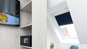 Una camera moderna con soffitto spiovente, una TV a parete, una scrivania con sedia e un lucernario.