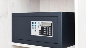 Una cassaforte nera con tastierino e display digitale, montata su un ripiano bianco.