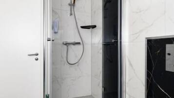 Une salle de bain moderne avec une douche à parois de verre, une porte blanche et un meuble-lavabo noir.