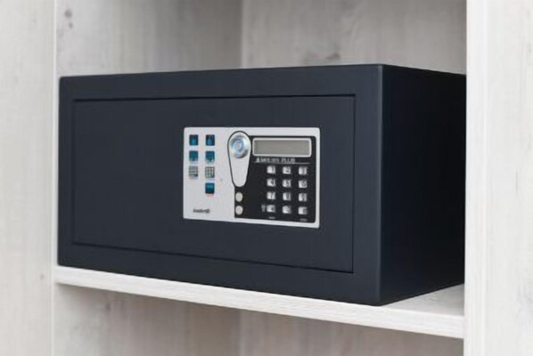 A black safe with a keypad and a digital display, mounted on a white shelf.