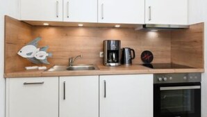A modern kitchen with white cabinets, a wooden countertop, a coffee maker, and an oven. - House Strandkorb apartment Strandkob 6 (Bensersiel)