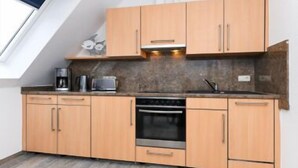 Eine Küche mit Holzausstattung, einer Mikrowelle, einer Kaffeemaschine und einem Backofen.