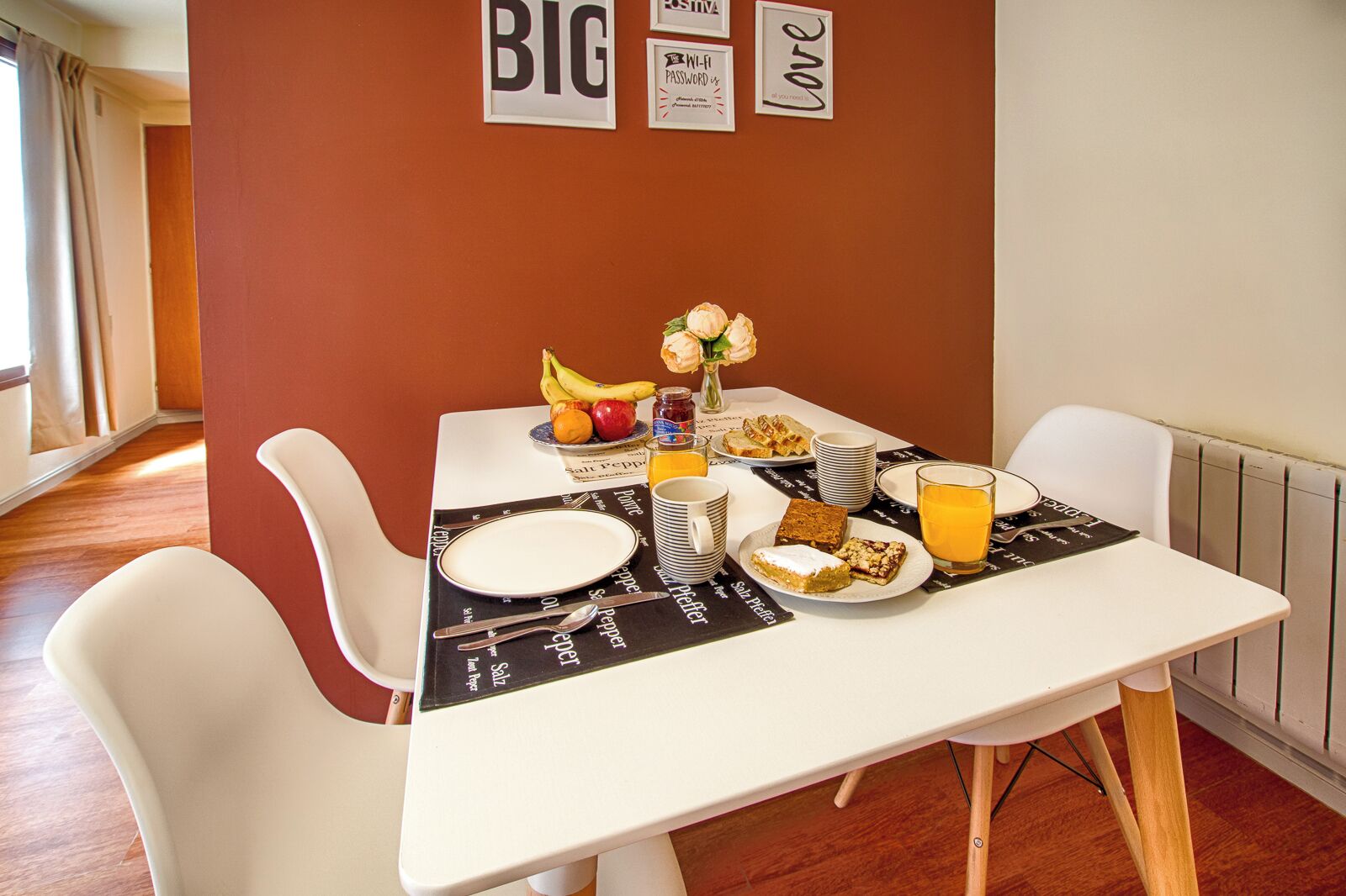 Ein Esszimmer mit gedecktem Tisch, Geschirr, Besteck und Speisen, mit roter Wand und Text im Hintergrund.