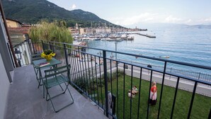 A balcony with a view of a marina, a grassy area, and a mountain in the background. - Apartment with a balcony overlooking the harbor (Salò)