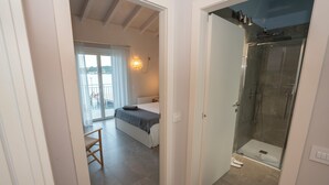 A modern bedroom with a bed, a bedside table, and a view of a balcony. - Apartment with a balcony overlooking the harbor (Salò)