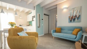 A modern living room with a mustard-colored armchair and a blue sofa with mustard cushions. - Apartment with a balcony overlooking the harbor (Salò)