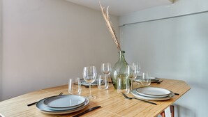 Een gedekte eettafel met borden, glazen en bestek, inclusief een vaas met gedroogde planten.