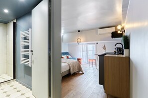 A modern bedroom with a bed, bedside table, and a view of the living area. - Charming Studio Center of Paris With AC (Paris)