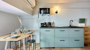 Een moderne keuken met een inbouwmagnetron, een koffiezetapparaat en een spoelbak. Er staat een eettafel gedekt met borden en glazen.