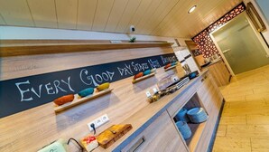 A modern hotel reception area with a wooden counter, a chalkboard with the text "EVERY GOOD DAY STARTS HERE," and various amenities like a scale, a small plant, and neatly stacked plates. - Hotel Franken (Forchheim)