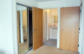 A room with a sliding door leading to a bathroom, a wooden door, and a carpeted floor.