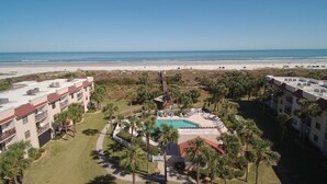 A resort with a swimming pool surrounded by palm trees, a beach view, and multiple buildings with balconies. - Ocean Village Club I35 (St. Augustine)