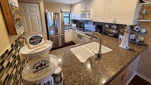 A modern kitchen with granite countertops, stainless steel appliances, and a two-basin sink. - Ocean Village Club I35 (St. Augustine)