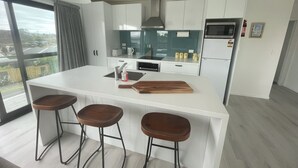 Eine moderne Küche mit einer zentralen Kochinsel, Barhocker, einer Mikrowelle und einem Kühlschrank.