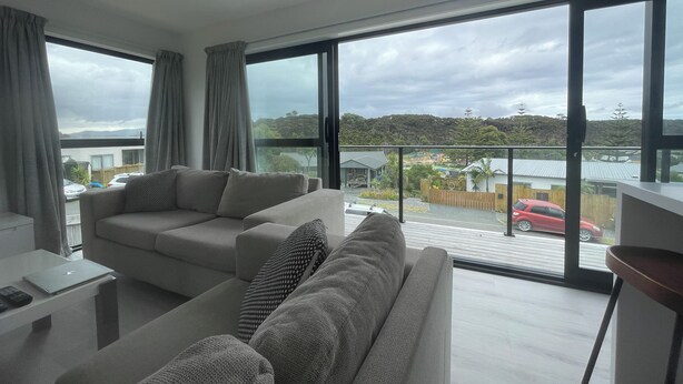 Ein modernes Wohnzimmer mit großem Fenster, einer Couch und einem Couchtisch.