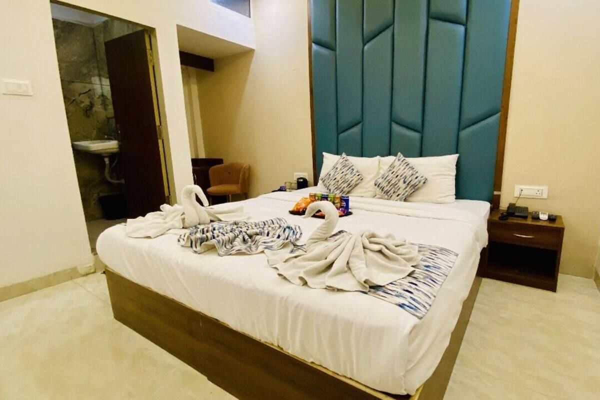 A hotel room with a large bed, a nightstand, a chair, and a bathroom visible through an open door.