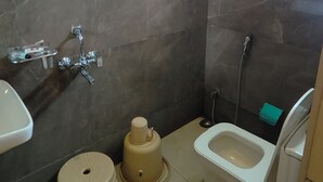 A bathroom with a shower, toilet, sink, and a small stool. - Hotel One Stay (Indore)