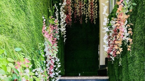 A staircase with artificial grass walls and hanging floral decorations. - Hotel One Stay (Indore)
